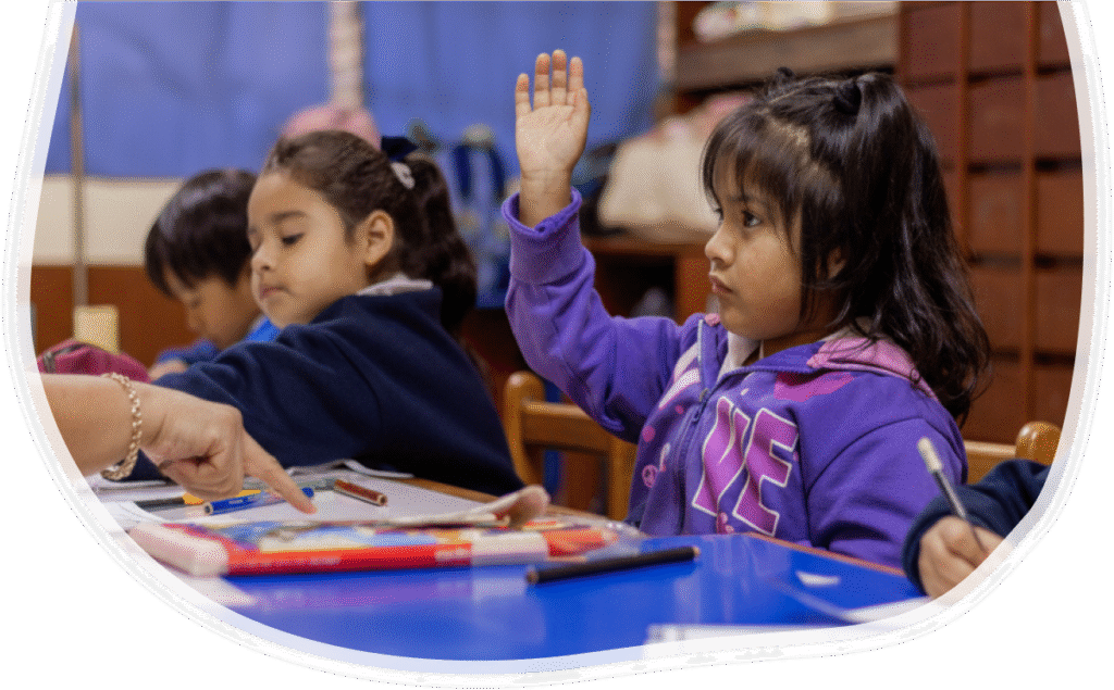 A young Deaf student raises her hand in class